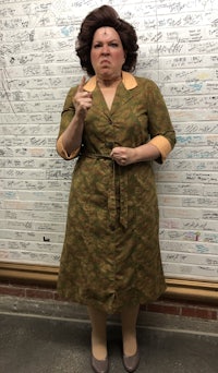 a woman in a green dress standing in front of a wall