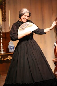 a woman in a black dress is holding a fan