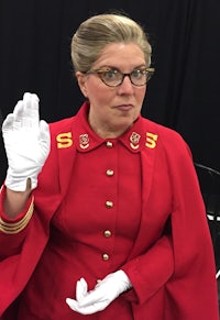 a woman in a red coat and white gloves making a hand gesture