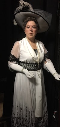 a woman in a white dress and hat is posing for a picture