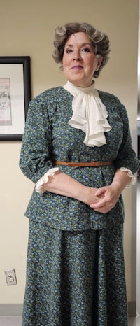 a woman in a green dress standing in a hallway