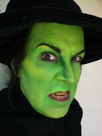 a woman wearing green makeup and a black hat